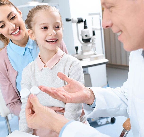 Doctor showing contact lenses to child patient