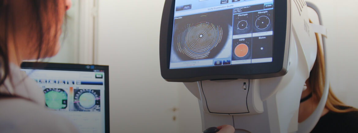 Optometrist using a corneal topography machine to examine a patient's eye